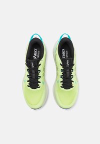 Scarpe da ginnastica giallo neon con lacci neri e parte superiore in rete. Accenti blu acqua sul tallone e sulla linguetta. Imbottitura Ortholite visibile nelle solette.