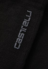 Tejido negro de punto con la palabra "Castelli" bordada en gris claro, posicionada verticalmente sobre el material.
