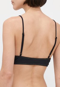 Zwarte bikinitop met dunne verstelbare bandjes en contrasterende stiksels. Soepele stof met een eenvoudig ontwerp, met een sluiting aan de achterkant.