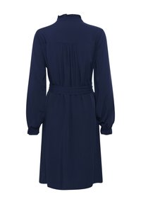 Abito blu navy con maniche lunghe a sbuffo, colletto arricciato, vita strizzata e dettagli plissettati sulla parte posteriore. Tessuto liscio con una leggera lucentezza.
