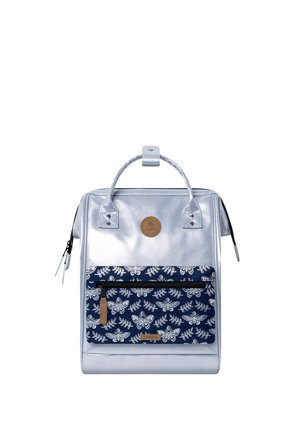 Silberner rechteckiger Rucksack mit Tragegriff oben, vordere Reißverschlusstasche mit weißen Schmetterlings- und Blattmustern auf marineblauem Hintergrund.