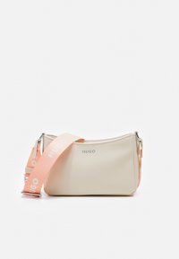 Beige synthetic shoulder bag with a smooth texture, featuring a pink strap with "HUGO" printed in white and a silver logo on the front.