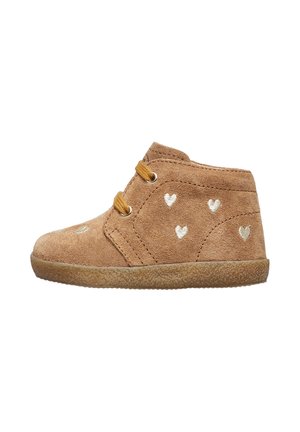 Stivaletti in suede color nocciola con suola in gomma, caratterizzati da motivi a cuore dorati, due fori e lacci marroni per la chiusura.