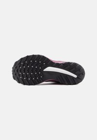 Trail running shoe outsole with a textured black rubber surface, featuring a prominent pink accent and white midsole detail.