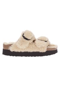 Sandale à enfiler en fausse fourrure crème avec deux sangles réglables, semelle en liège marron et semelle extérieure en caoutchouc noir texturé.