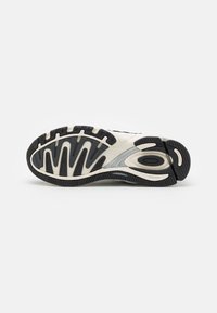 Semelle de chaussure avec motif de bande de roulement noir et blanc, sections de grip courbées et petit texte indiquant "ADIWear" et "TORSION SYSTEM" sur un fond uni.