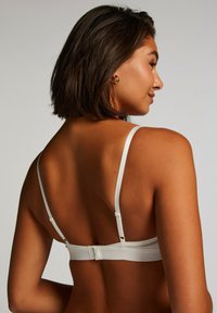 Witte beha met verstelbare banden, haak- en oogsluiting aan de achterkant, en een gladde stofstructuur voor comfort en ondersteuning.