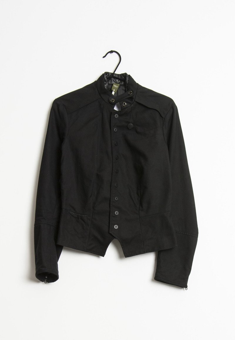 Svart, figursydd jacka med hög krage, knappstängning framtill och långa ärmar. Den har en slät yta och en lätt midjeinsnävning.