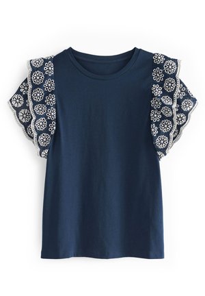 Haut bleu marine à manches courtes avec col rond et manches volantées en dentelle, broderies florales blanches et bords festonnés.