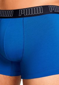 Boxer briefs in cotone blu con waistband elastico nero, caratterizzati dalla scritta bianca "PUMA". Texture liscia e vestibilità aderente con cuciture piatte.