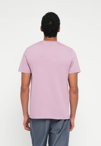 Trumpomis rankovėmis marškinėliai iš švelnios rožinės medvilnės su apvalia apykakle, pasižymintys lygiu paviršiumi ir laisvu siluetu. Be matomų grafinių elementų ar raštų.