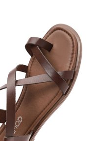 Ruskeat nahka sandaalit, joissa on ristikkäiset hihnat, pehmustettu pohja, sileä pinta ja kestävä pohja.