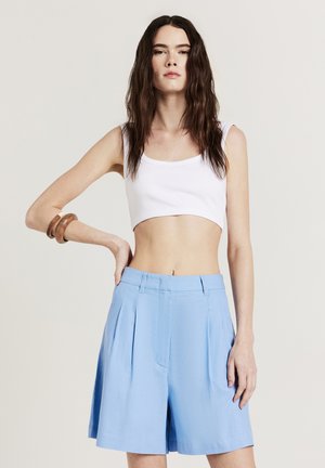 White crop top with a round neckline paired with high-waisted, pleated blue shorts, featuring a smooth texture and tailored fit.
