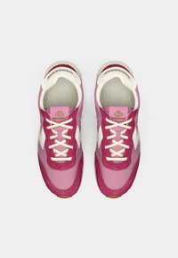 Pink sneakers with a suede and textile upper, featuring white accents, round laces, and a textured insole with logo details.