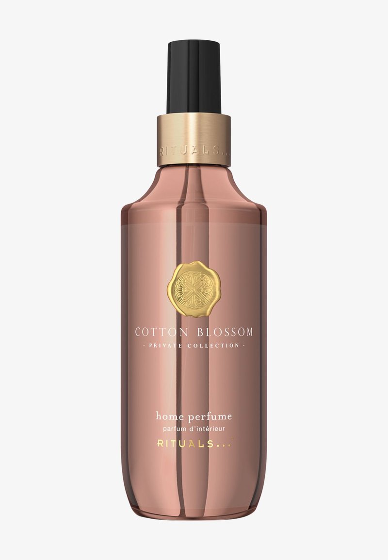 Profumo per ambienti Cotton Blossom in una bottiglia curva di vetro traslucido rosa con un nebulizzatore nero e un accento dorato sul tappo.