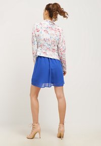 Floral-print blazer in pastel colors paired with a blue chiffon dress. Features a fitted design, long sleeves, and ankle boots with laces.