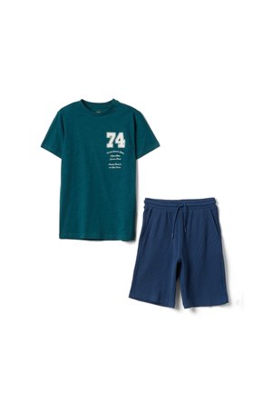 Turkoois T-shirt met korte mouwen met witte "74" opdruk en marineblauwe shorts met trekkoord, casual tweedelige outfit plat gelegd op een witte achtergrond.