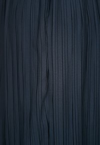 Mörkblått tyg med vertikala smala veck som skapar texturerade, jämnt fördelade ränder.