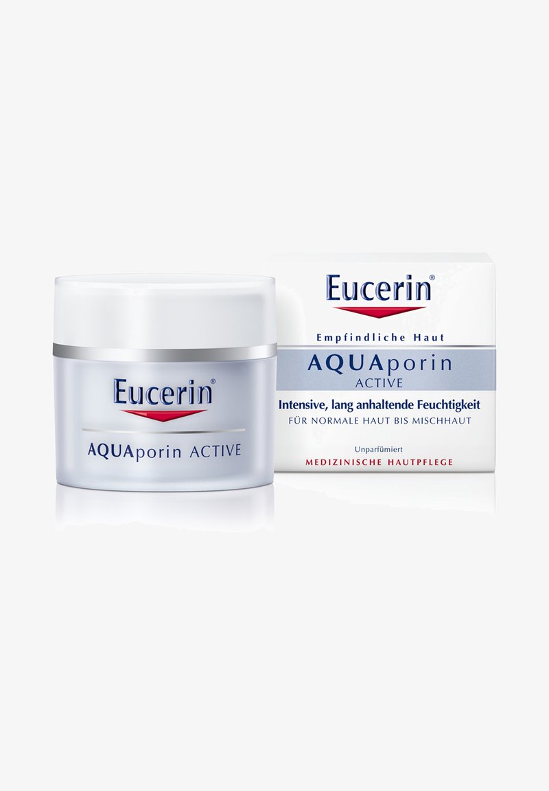 Eucerin AQUAporin ACTIVE Feuchtigkeitscreme in einem klaren Glasbehälter mit einem silbernen Band. Die Kartonverpackung zeigt blau-weiße Farben mit informativem Text.