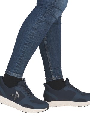 Navy athletic shoes with mesh upper, contrasting gray accents, cushioned white sole, and black socks. Paired with fitted denim jeans.