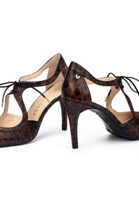 Zapatos de tacón alto con estampado de leopardo, diseño recortado, cordones negros y exterior de cuero texturizado. Acentos dorados y un tacón delgado.