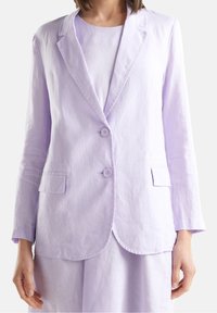 Fioletowo-liliowy lniany żakiet z klapami z wycięciem, dwoma guzikami zapinany z przodu, kieszeniami z przodu oraz guzikami na rękawach. Gładka, miękka faktura.