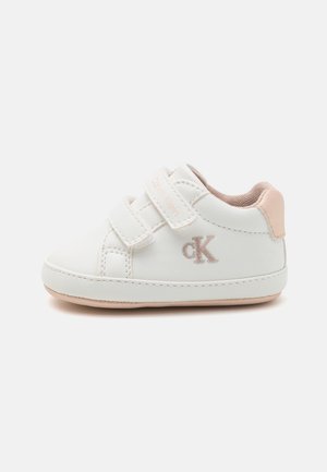 Sneaker bianca con due cinturini in Velcro, accento beige chiaro sul tallone e piccolo logo ricamato di colore chiaro. Texture in pelle liscia.