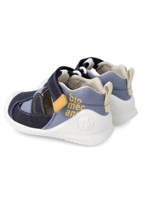 Deportivas de tela azules y marinas con suelas blancas, que cuentan con detalles amarillos, una correa de Velcro y un diseño abierto para ventilación y comodidad.