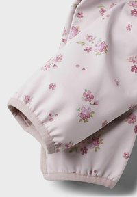 Ljusrosa tygärm med ett blommönster i rosa och gröna accenter. Detaljerade manschetter och en mjuk, texturerad foder är synliga.