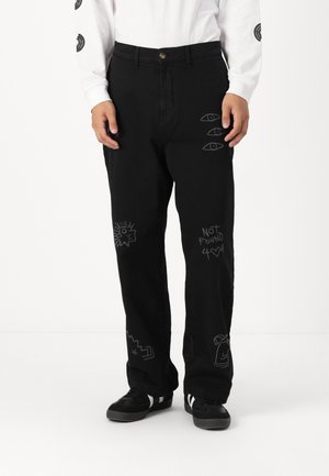 Pantalones negros con diversos dibujos en estilo graffiti en blanco, incluyendo ojos y texto. Están hechos de una tela duradera y tienen un corte relajado.