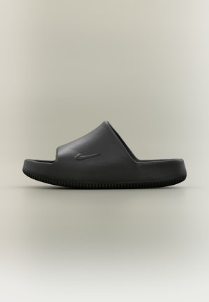 Μαύρο σανδάλι slide Nike με καλουπωμένο πέλμα και υφασμένη σόλα, εμφανιζόμενο σε πλευρική προφίλ σε ουδέτερο φόντο.