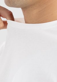 Hvid bomulds T-shirt med rund halsudskæring, der har en glat tekstur og en afslappet pasform. Kraven er let rullet eller trukket tilbage.