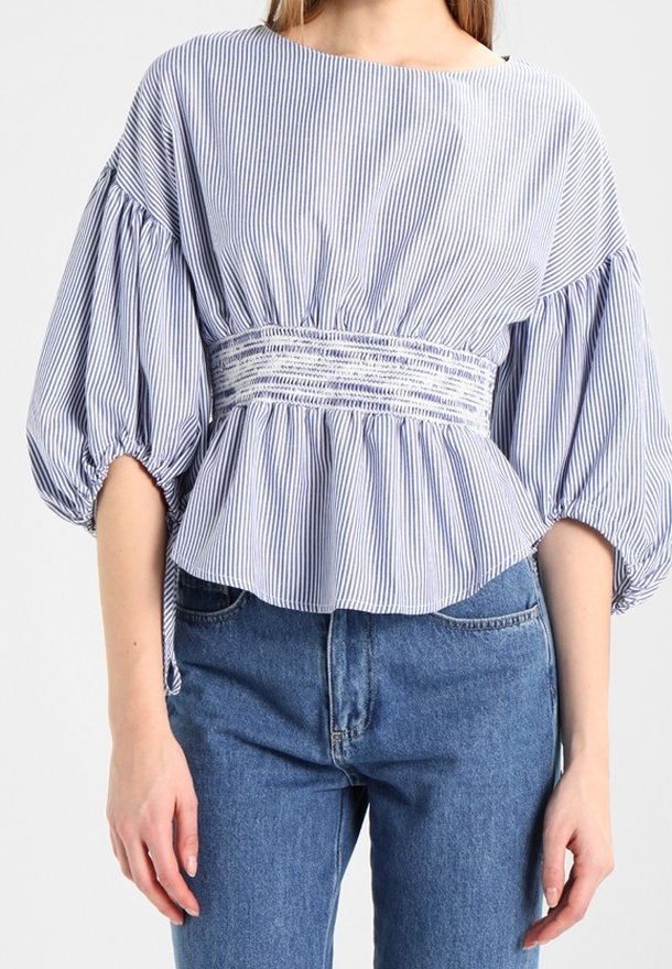 Blå och vit randig blus med vid halsringning, ballongärmar, samlad midja och mjukt tyg. Kombinerad med ljusblåjeans.