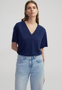 Navyblauw v-hals t-shirt van zachte stof, met korte mouwen, een relaxte pasvorm en gecombineerd met lichtblauwe high-waisted jeans.