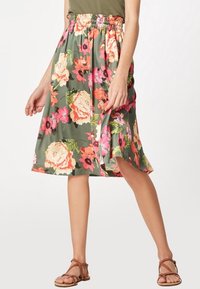 Flo floral rok met een gerimpelde tailleband, versierd met een mix van roze, oranje en groene bloemen op een groene achtergrond. Lichtgewicht stof en knielang.