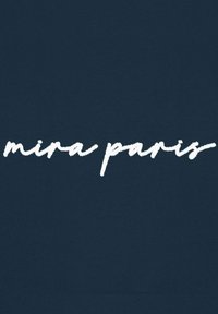 Tessuto blu navy con testo bianco in stile scrittura a mano che dice "mira paris." Il testo appare giocoso ed è centrato sul materiale.