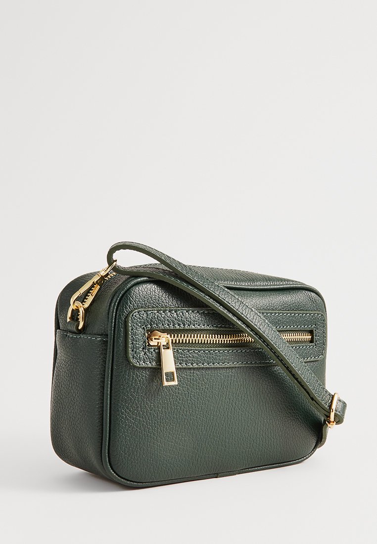 Sac bandoulière en cuir vert avec une finition texturée, doté d'une poche zippée à l'avant et d'un accent en métallisé doré. Sangle ajustable incluse.