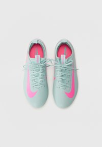 Svetlomodré futbalové topánky s ružovým Nike logom, textúrovaný zvršok a koordinujúce šnúrky; obsahujú pútko na päte.