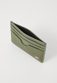Green leather cardholder with multiple card slots, a textured surface, and a small logo accent on the bottom corner.