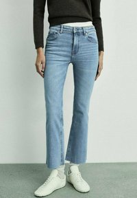 Jeans de culoare albastru deschis, cu talie înaltă și picior evazat. Realizați din denim cu o ușoară decolorare, având cinci buzunare și închidere cu fermoar frontal.