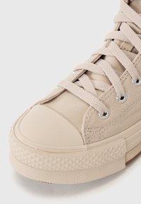 Beez värvi kanvas sneaker, millel on kummist varvastekork, tekstureeritud tallad ja klassikaline nöörimise disain. Hõbedased silmad rõhutavad kogu neutraalset välimust.