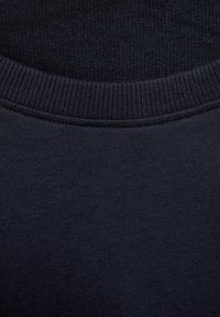 Tessuto a maglia blu navy con scollatura a costine e superficie liscia, con dettaglio di cucitura piatta lungo il bordo.