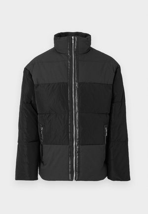 Giacca puffa nera con pannelli opachi e lucidi a contrasto, colletto alto e due tasche laterali con zip. Cerniera frontale a tutta lunghezza.