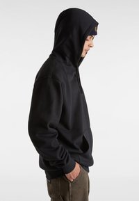 Felpa nera con cappuccio realizzata in morbido materiale, caratterizzata da una tasca a marsupio e polsini a costine. Il design è minimale, senza loghi visibili.