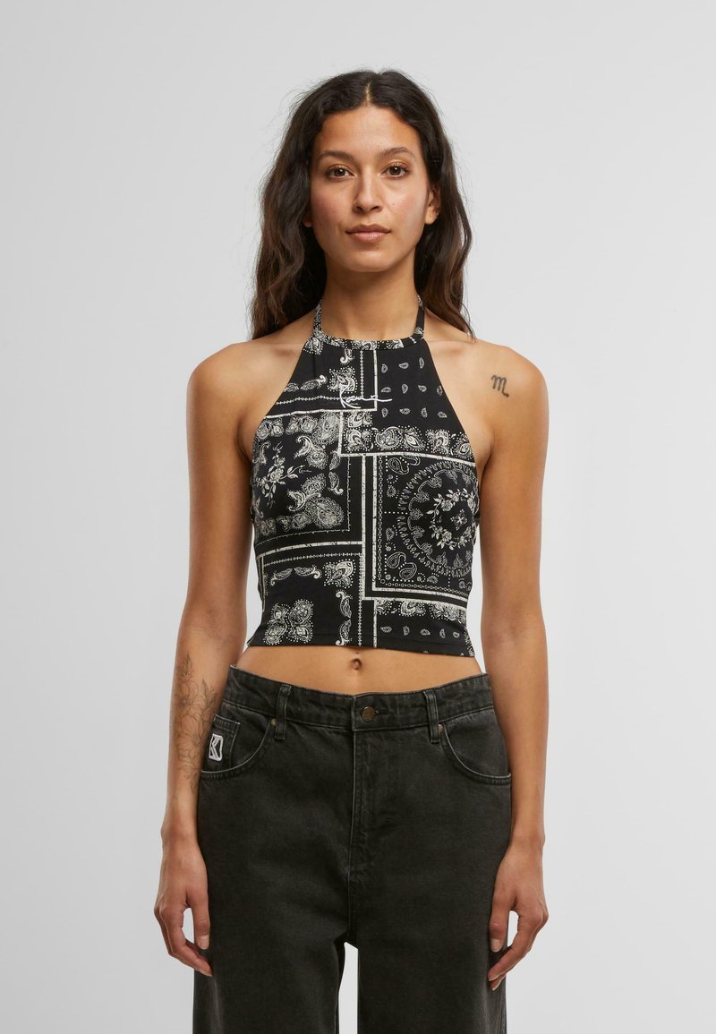 Mustmust halsika crop top, mille on valged paisleide ja geomeetrilised mustrid, valmistatud kergest kangast, paaritatud tumedate teksadega.