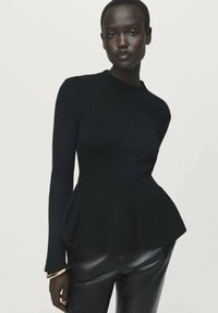 Pullover nero a costine con maniche lunghe e orlo a peplum, realizzato in un morbido tessuto a maglia. Abbinato a pantaloni in ecopelle neri e bracciale a manica dorato.