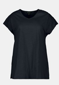 Camiseta negra de manga corta hecha de tela liviana con cuello en V y acentos texturizados en las costuras de los hombros. Dobladillo redondeado.