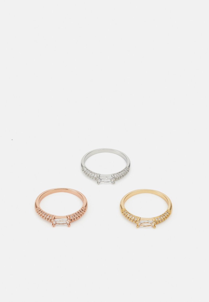 Three rings displayed: one rose gold with clear stones, one silver with clear stones, and one yellow gold with clear stones, all featuring a structured band.