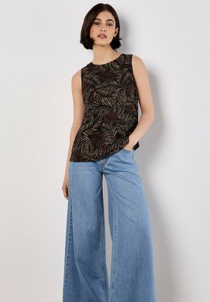 Haut sans manches noir avec un motif de feuilles dans des nuances de brun et d'or, associé à un jean ample bleu clair, offrant une coupe décontractée.