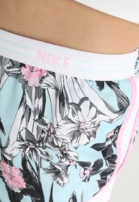 Nike shorts feature a light blue fabric with a black and pink floral pattern, a white elastic waistband with pink branding, and pink accents.